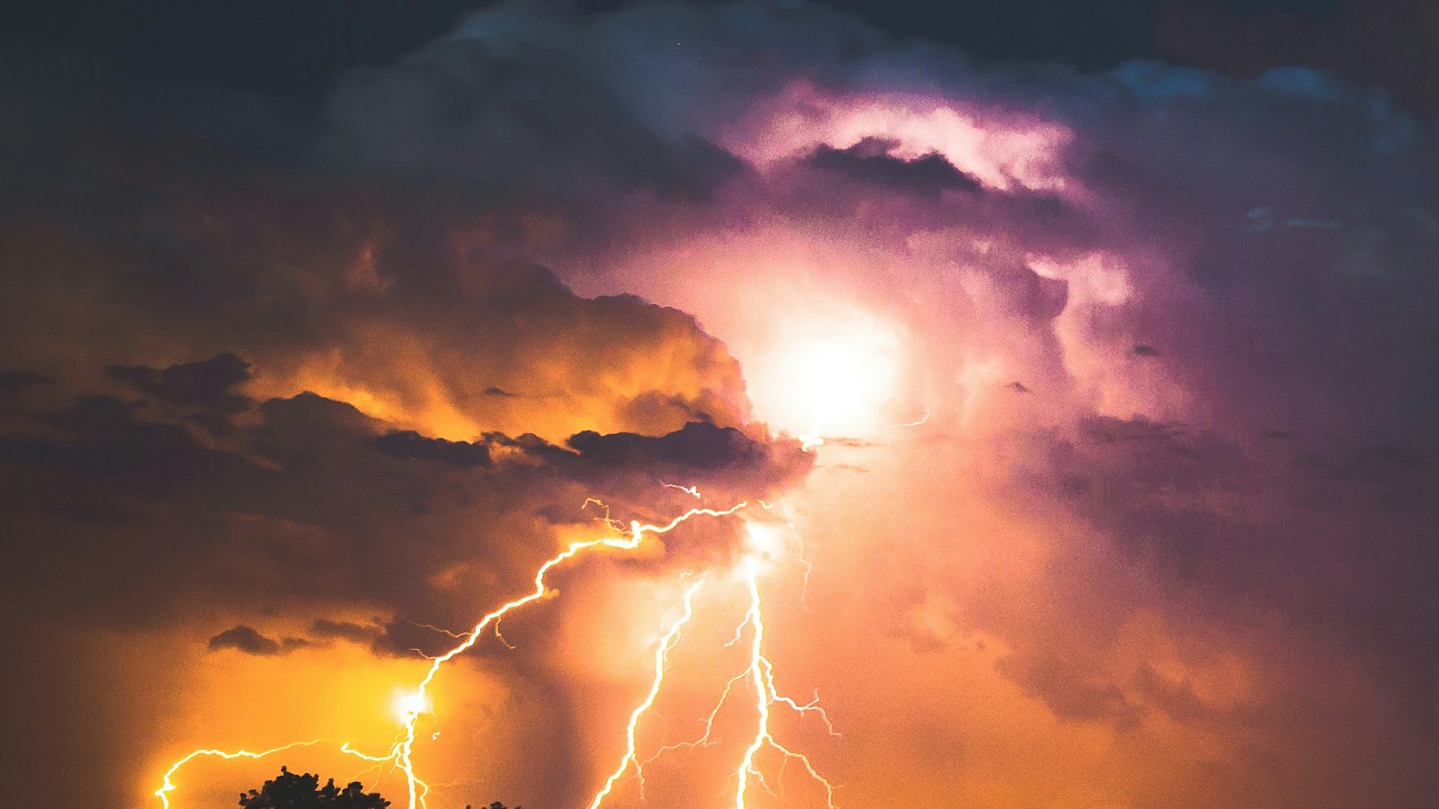 Lightning striking through storm clouds at night